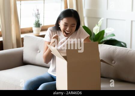 La jeune fille asiatique enchantée a surplaisanté avec le paquet de commande en ligne Banque D'Images