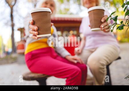 Amis ayant du café parfumé dans le parc Banque D'Images