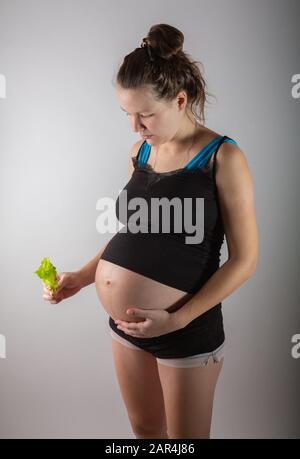 Femme enceinte tenant une salade fraîche en studio Banque D'Images