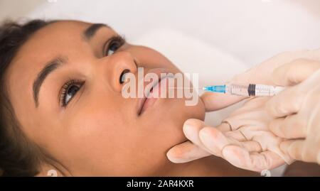 Injection de beauté. Femme afro faisant la procédure d'augmentation de lèvre Banque D'Images