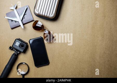 Vue de dessus des accessoires utilisés pour les voyageurs de loisirs sur un fond marron. Accessoires de voyage et espace de copie. Concept d'accessoires de voyage de vue supérieure. Banque D'Images