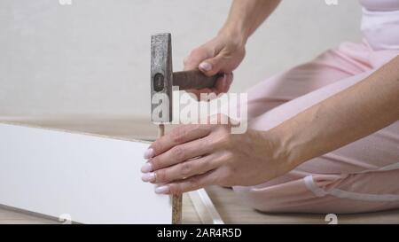 femme collecte des meubles blancs à la maison à l'aide d'un marteau. Gros plan. Banque D'Images