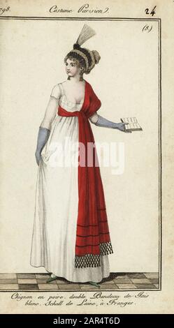 Femme dans les modes du 25 février 1798. Elle porte ses cheveux dans un petit pain en forme de poire sous un double bandeau dans un jet blanc. Sa châle à franges en laine rouge est attachée autour de la taille haute. Robe simple blanche à décolleté. Mignon en poire. Double bandeau de jais blanc. Schall de laine, une frange. 25 février 1798. Gravure en copperplate de couleur à la main du Journal des modes et Dames de Pierre de la Mesangere, Paris, 1798. Les illustrations du volume 1 étaient celles de Carle Vernet, Claude Louis Desrais et Philibert Louis Debucourt. Banque D'Images