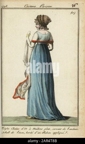Femme en robe bleue avec semoule sous la forme de 1798. Elle porte une triple chaîne en or avec des maillons plats comme un bandeau. Son châle à linon est bordé d'un ruban appliqué rouge. Triple chaine d'Or un maillons plats serviteur de bandeau. Schall de linon, borde d'un ruban appliqué. Gravure en copperplate de couleur à la main du Journal des modes et Dames de Pierre de la Mesangere, Paris, 1798. Les illustrations du volume 1 étaient celles de Carle Vernet, Claude Louis Desrais et Philibert Louis Debucourt. Banque D'Images