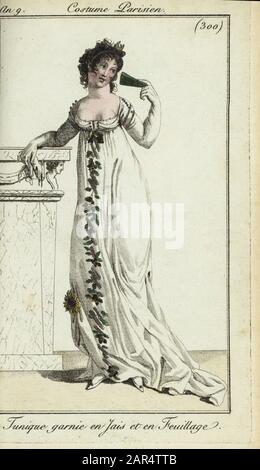 Femme à la mode ou Merveilleuse en robe tunique basse, 1801. Sa robe est décorée de jet et de feuillage. Elle se penche sur une pièce de mantilité et tient un ventilateur. Tunique garnie en Jais et en Feuillon. Gravure en copperplate de couleur à la main du Journal des modes et Dames de Pierre de la Mesangere, Paris, 1801. Les illustrations du volume 4 étaient Carle Vernet, Bosio, Dutailly et Philibert Louis Debucourt. Banque D'Images