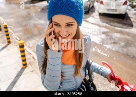 Femme utilisant son téléphone marchant dans la boue et décongeler la neige Banque D'Images