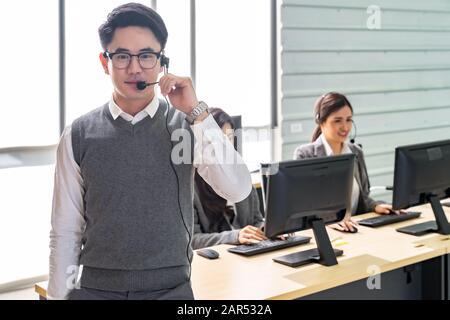 Portrait de jeune adulte friendly et la confiance avec l'homme de l'opérateur des casques et son équipe de travail dans un centre d'appels que le service client et technique sup Banque D'Images