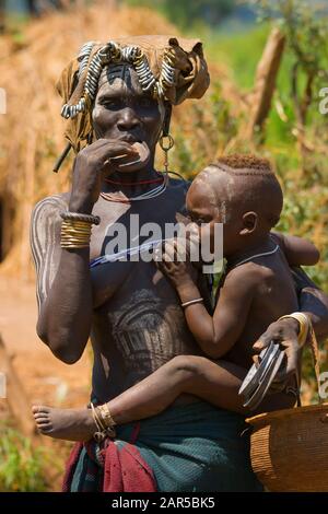 Femme Mursi allaitant bébé et vendant des assiettes. Les femmes de Morsi sont célèbres de porter des plaques dans leurs lèvres inférieures. La raison de ce "ornement" est Banque D'Images