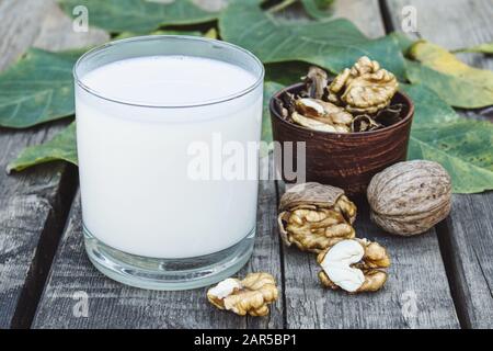 Un verre de lait blanc et de noix sur une vieille table en bois. Lait de légumes à base de noix. Éco-nourriture. Le keto est en train de boire. Banque D'Images