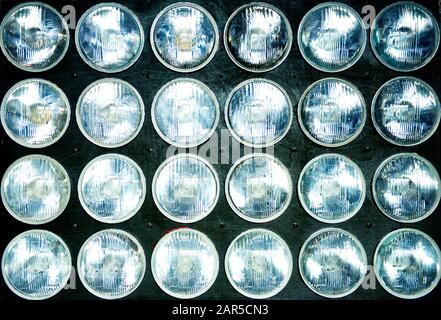 panneau en bois avec un grand nombre de phares ronds installés dans celui-ci. Contexte. Concept d'éclairage lumineux, élément de conception. Banque D'Images