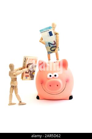 Une poupée en bois contient de l'argent pour mettre dans une banque de porc (concept d'épargne) Banque D'Images