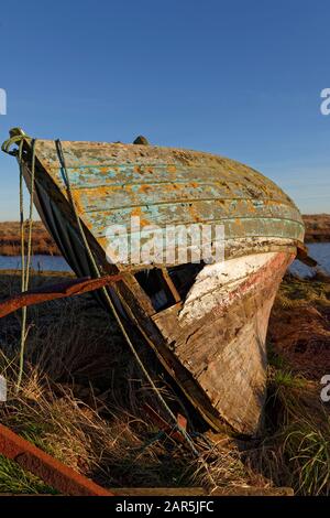 Vue rapprochée de l'arc endommagé d'un petit bateau de pêche en bois côtier à côté d'un petit estuaire dans la Réserve naturelle de St Cyrus. Banque D'Images