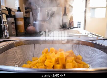 Morceaux de mangue chaude pelés et en forme de carré dans un métal passoire dans la cuisine Banque D'Images