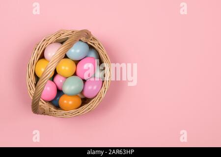 Fond de Pâques avec des œufs de pâques de couleur pastel dans un panier sur un fond rose avec espace pour un exemplaire vu d'un grand angle Banque D'Images