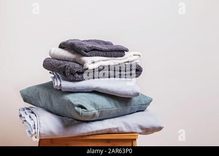 Pile d'articles textiles maison pliés propres près du mur blanc. Banque D'Images