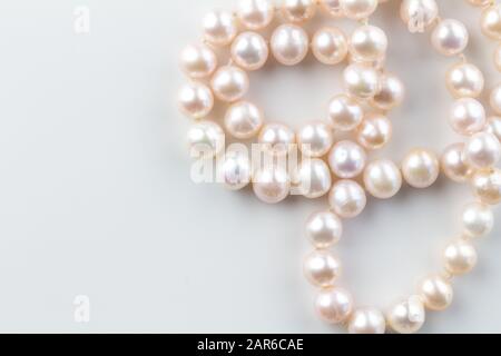 Collier de perles fond avec une chaîne de perles roses isolées sur fond blanc - photo de vue de dessus avec espace texte Banque D'Images