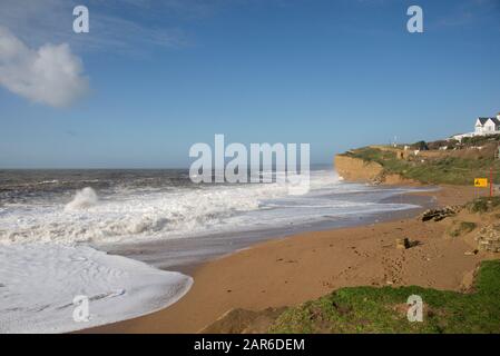 De hautes vagues blanches qui jetent les falaises de plage et de grès à marée haute lors d'une belle journée à Hive Beach, près de West Bay, Dorset, janvier Banque D'Images