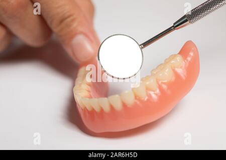 Prothèse de prothèse dentaire dans la main du dentiste orthodontiste du médecin, en vérifiant avec miroir Banque D'Images