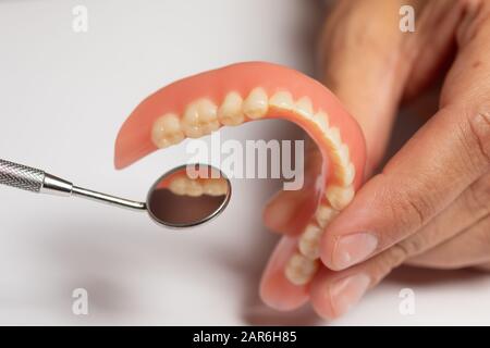 Prothèse de prothèse dentaire dans la main du dentiste orthodontiste du médecin, en vérifiant avec miroir Banque D'Images