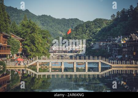 Feng Huang, Chine - Août 2019 : drapeau chinois fluant au-dessus de l'un des nombreux ponts au-dessus de la rivière Tuo Jiang dans la vieille ville de Fenghuang connue sous le nom de Pho Banque D'Images