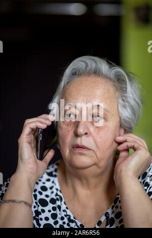 Portrait femme senior parlant sur smartphone à la maison. Banque D'Images