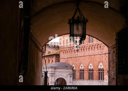 Piazza del Campo, aperçue à travers une arche sur l'une des nombreuses rues étroites, toutes menant au centre-ville, Sienne, Italie. Banque D'Images