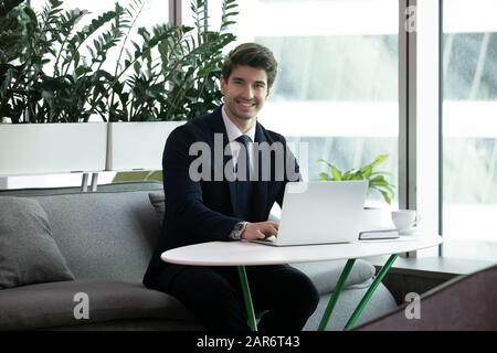 Un jeune homme d'affaires souriant et confiant regardant l'appareil photo. Banque D'Images