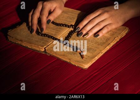 Le rosaire de perles noires sur l'ancien livre de Sainte bible ouvert. Banque D'Images