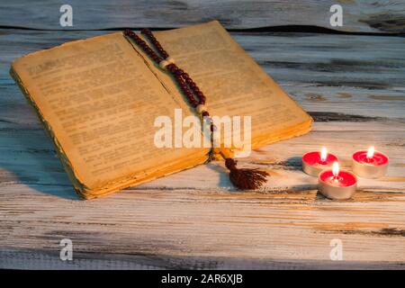 Ouvrir la bible avec des bougies rosaaires. Banque D'Images