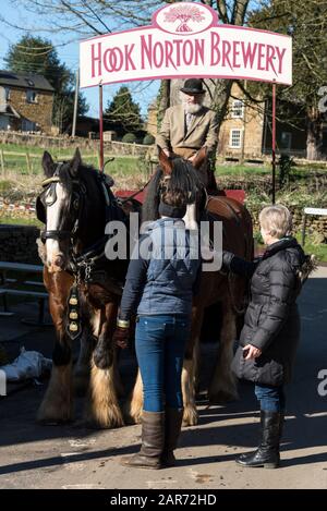 Un petit groupe de visiteurs se réunissent pour admirer un cheval de dragons et de chire conduit par Drayman, Roger Hughes, qui fait la première livraison de bière à l'un des vilags Banque D'Images