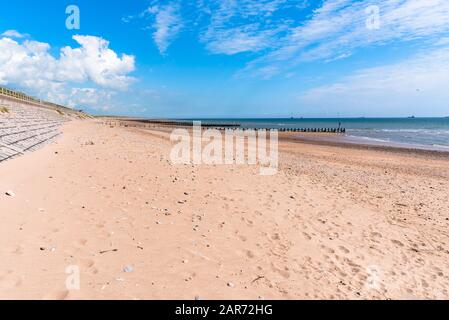 Plage de sable déserte face à une éolienne en mer une journée ensoleillée de printemps Banque D'Images