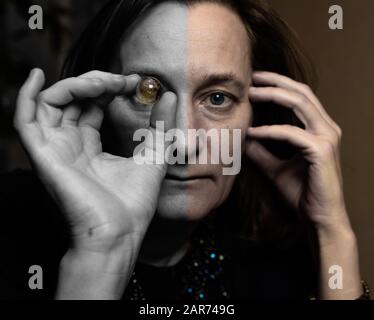 oncept: une femme mûre tient une petite boule de verre au niveau des yeux. Allégorie de magie, occultisme, divination Banque D'Images