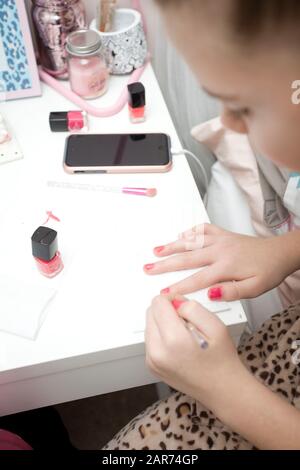 Fille de onze ans peignant ses ongles dans sa chambre Banque D'Images