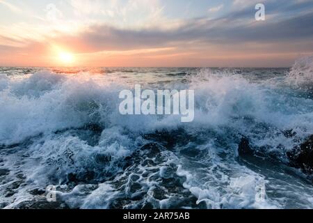 L'eau de l'océan Se Rince à la rive comme le soleil se fixe sur l'horizon de l'océan Banque D'Images