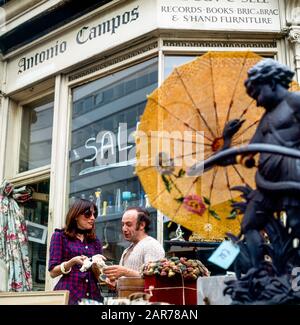 Londres, années 1970, femme shopping et marchand d'antiquités, exposition extérieure de rue, Kensington, Angleterre, Royaume-Uni, GB, Grande-Bretagne, Banque D'Images