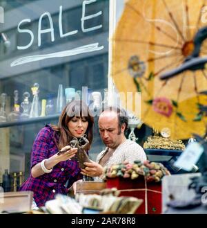 Londres 1970, femme shopping et marchand d'antiquités, rue à l'extérieur de magasin d'exposition, Kensington, Angleterre, Royaume-Uni, GB, Grande-Bretagne, Banque D'Images