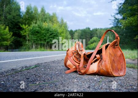 Sac en cuir orange sur le côté d'une route de campagne le jour de l'été. Grand angle. Espace de copie Banque D'Images