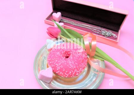 Concept de Saint-Valentin. Fleurs, tulipes roses. Coeurs roses, boîte cadeau. Beignet rose. Couche plate, espace de copie Banque D'Images