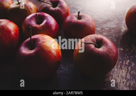 Pommes rouges, fraîches, brillantes et biologiques cultivées, sur une table et lumière venant de la fenêtre Banque D'Images