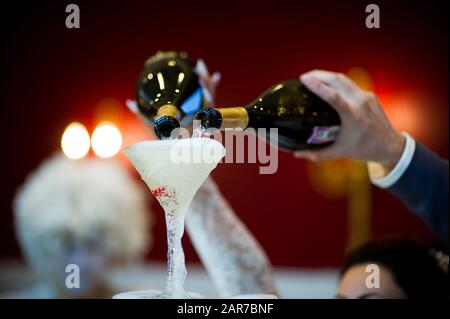 les mains de la mariée et du marié verser du champagne sur une lame des verres pour qu'il déborde sur toutes les lunettes Banque D'Images