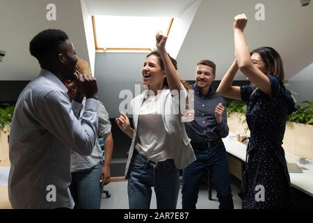 Les collègues multiethniques excités ont du plaisir à faire la fête au bureau Banque D'Images