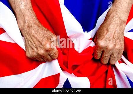 Les mains d'un homme âgé ont un drapeau britannique. Le concept de prendre soin des retraités. Banque D'Images