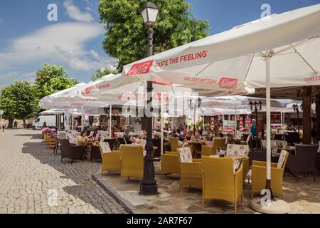 Nessebar, BULGARIE - 26 JUIN 2019: Les gens mangent dans un café en plein air et se cachent du soleil sous de grandes auvents le jour chaud d'été. Vieille ville de Nessebar, le Banque D'Images