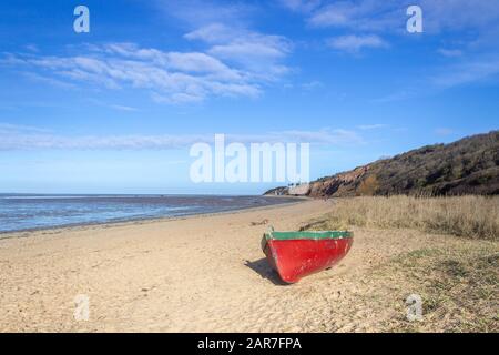 Bateau rouge sur la plage à côté de l'estuaire de la Dee à Thurstaston, Wirral Banque D'Images