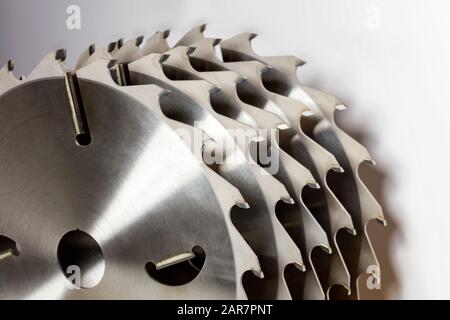 Jeu de scies circulaires en carbure pour couper le gros plan du bois, les dents de coupe et le faisceau lumineux en réflexion, image avec espace de copie. Banque D'Images