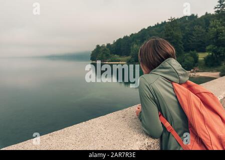 Randonneur féminin debout sur le pont et regardant le lac, vue arrière de la femme dans les vêtements de sport à l'extérieur Banque D'Images