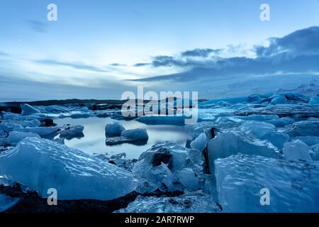 glacier d'islande jokulsarlon dans les icebergs du soir flottant sur l'eau froide paisible après coucher de soleil avec le ciel dramatique . Banque D'Images