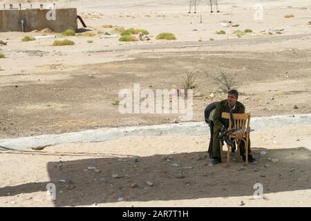 Louxor, Egypte; Afrique. Un militaire ou un garde de police est assis au bord de la route près de Louxor. Banque D'Images