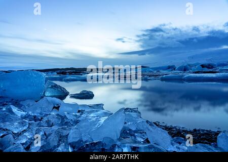 glacier d'islande jokulsarlon dans les icebergs du soir flottant sur l'eau froide paisible après coucher de soleil avec le ciel dramatique . Banque D'Images