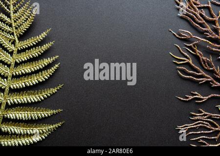 Fond floral minimaliste avec feuilles de fougères dorées et branche de corail Banque D'Images